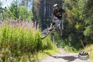 Un rider salta in sell alla sua MTB e fa un trick in volo toccando della vegetazione con la ruota posteriore